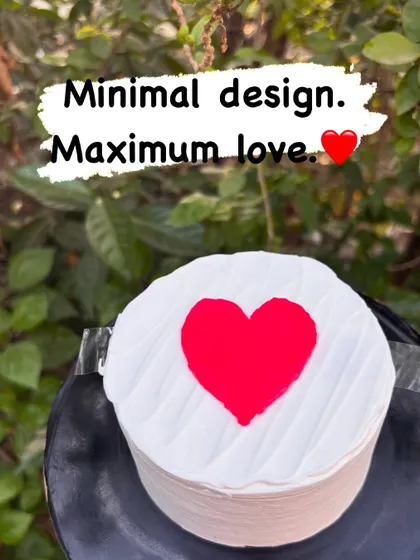 Minimal design, maximum love. This simple round cake features a clean, textured white buttercream and a single, bold red heart in the center, proving that simplicity can be stunning.