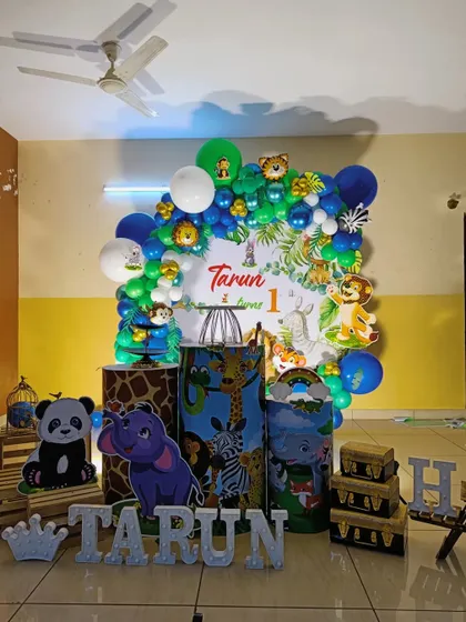 The full jungle party setup for Tarun's first birthday, complete with themed pedestals and large animal cutouts like a panda and elephant.