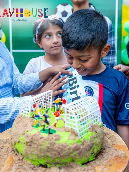 A close-up of the birthday boy admiring his unique football-themed cake, a moment of pure delight.