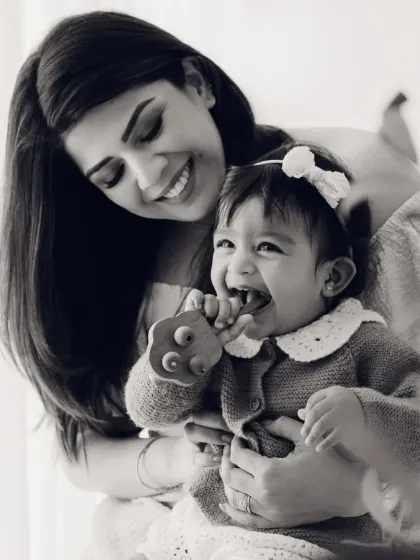 A mother holds her teething baby in this candid black and white photo. It's a real, beautiful moment of motherhood.