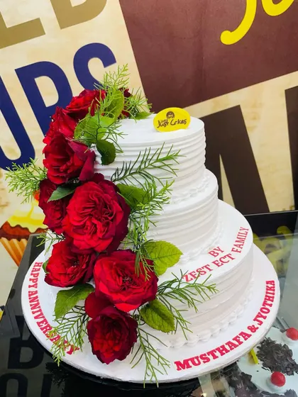 A classic 4kg three-tiered anniversary cake with simple white frosting, elegantly decorated with a cascade of fresh red roses.