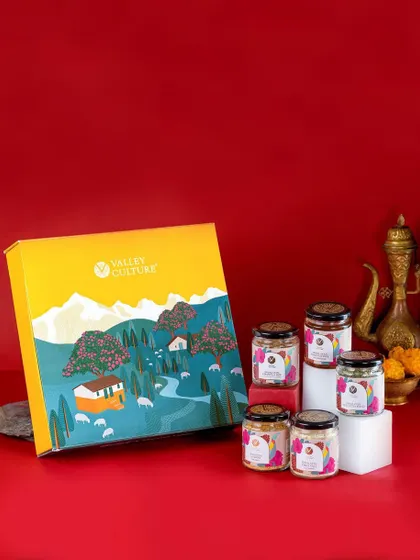 A vibrant shot of a Valley Culture gift box against a bold red background. The traditional brass pot adds a touch of ethnic elegance, making it an ideal image for festive gifting campaigns.
