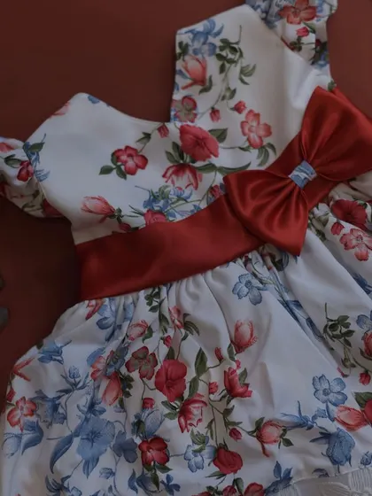 A beautiful white floral print dress with a bold red satin sash and bow. The contrast between the delicate print and the rich red color is simply stunning.