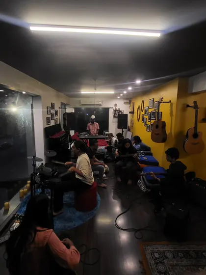A wide shot of a late-night rehearsal. The space is versatile, transforming from a bright workshop venue by day to a moody jam pad by night.