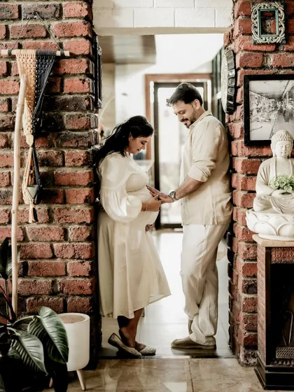 A beautiful, serene portrait of the couple in a rustic brick hallway. Their hands meeting on her baby bump is the central focus of this quiet, loving moment.