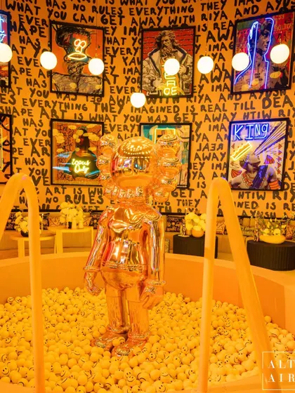 A golden Kaws-inspired figure stands tall in a pit of yellow smiley-face balls. This installation was the heart of the Graffiti room, blending street art cool with a playful, luxurious twist that was perfect for photo moments.