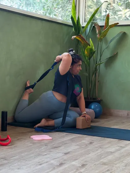 A student uses a strap to assist in a deep quad stretch, showing how props can make challenging poses more accessible.