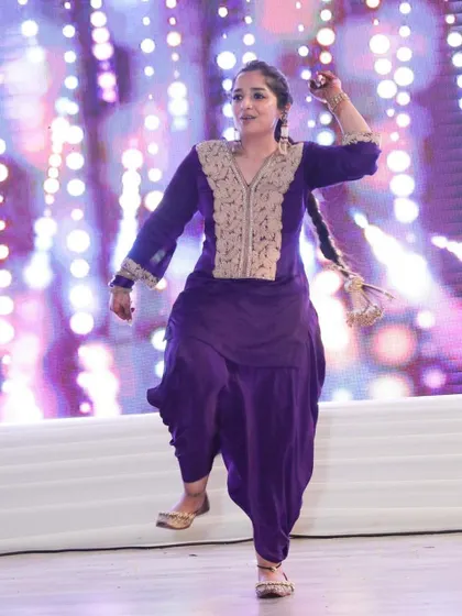 A powerful Bhangra pose captured on stage. This folk dance is all about strength, energy, and celebrating with every step.