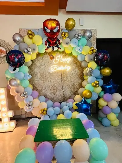 A unique pastel-colored Spiderman theme for a 4th birthday. This setup combines the popular superhero with a softer color palette, a circular balloon arch, and a kids' table.