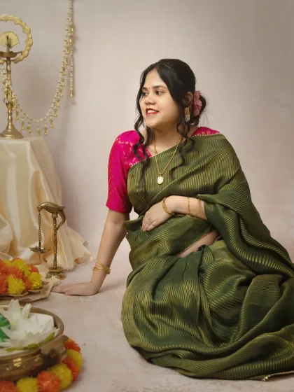 A candid solo shot of the mother-to-be, looking off-camera with a gentle smile. The soft lighting and the rich color of her saree make this a beautiful, reflective portrait.