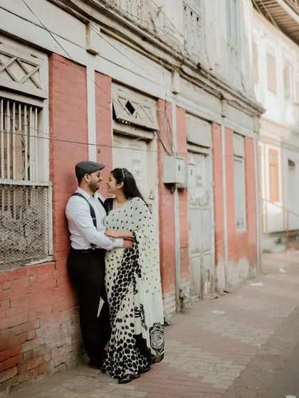 A wider shot showing the couple against a rustic red brick wall. The setting adds so much character to their urban love story.