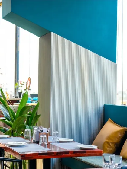Texture plays a vital role in our designs. Here, a fluted white panel contrasts with a solid block of teal, creating a visually interesting and modern detail within the bar's seating area.