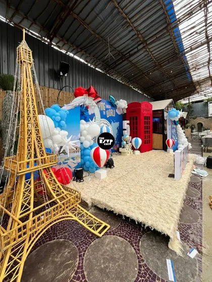 A grand backdrop for an 'Around the World' party, featuring a giant Eiffel Tower prop and a classic red London telephone booth.