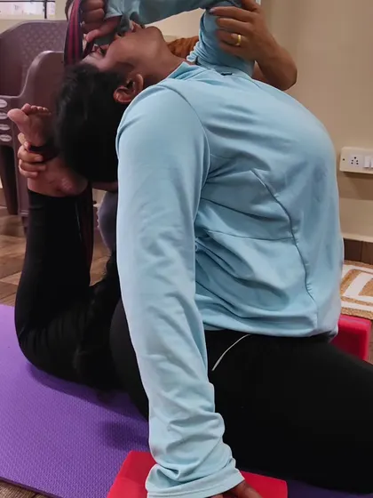 A closer look at the hands on assistance provided to help a student safely achieve a deep backbend in Poorna Rajkapotasana.