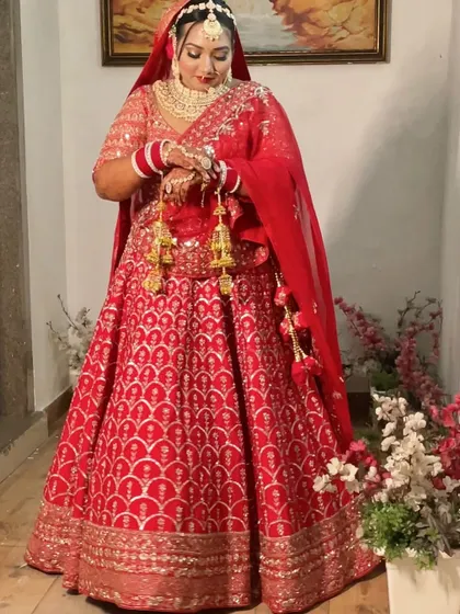 The bride looking at her kalire, a classic pose that also shows off her detailed eye makeup and beautiful red bangles.