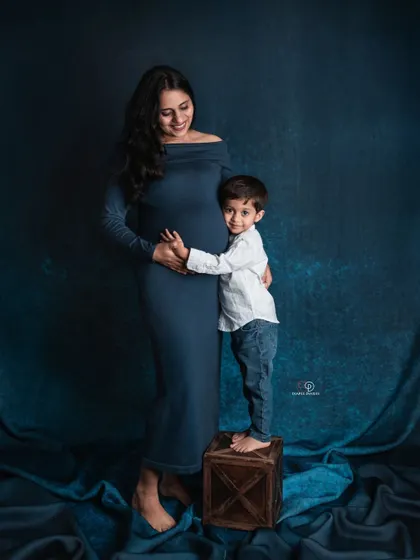 A sweet hug for the baby bump from the big-brother-to-be. The deep blue backdrop and simple outfits keep the focus on this heartwarming family moment.