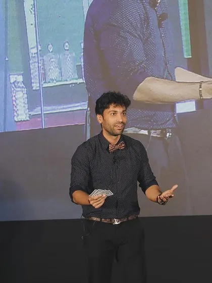 Performing sleight of hand with cards, a fundamental skill for any magician, presented here for a large corporate audience.