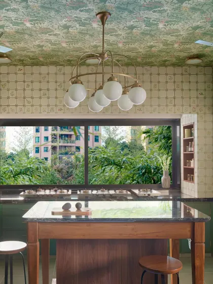 This kitchen, with its view of the lush outdoors, is the heart of the home, designed for slow mornings and shared meals. The island becomes a natural gathering spot, while the large window invites nature in, creating a space that feels both expansive and intimate.