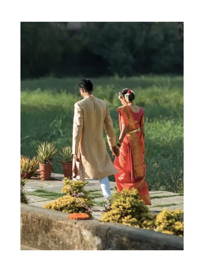 The couple walks away hand in hand through a lush green path. A quiet, candid moment that feels both peaceful and romantic.
