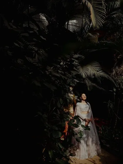 An artistic shot of a couple in a garden at night, with dramatic lighting highlighting the bride. This demonstrates our creative use of light and shadow.