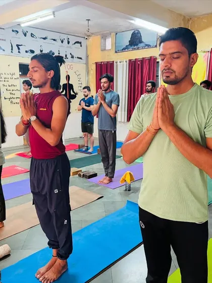 Students stand in Samasthiti with hands in prayer. This is the starting and ending point for many sequences, a pose of equal standing and mindful presence.
