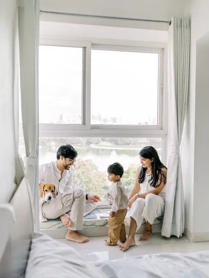 A family sitting together by a large window overlooking a lake. Their pet beagle is right there with them, a true member of the family.
