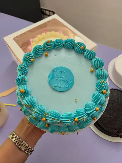 A simple but elegant Father's Day cake with blue piping and gold sprinkles.