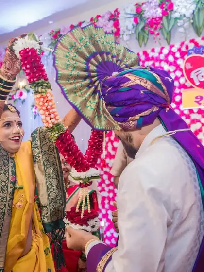 The bride joyfully places the garland over the groom during the varmala exchange, a classic and fun wedding moment.
