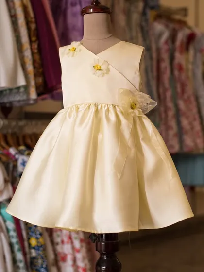 A simple and elegant cream-colored satin dress. This versatile piece is adorned with three delicate floral appliqués, making it a beautiful choice for a variety of special occasions.