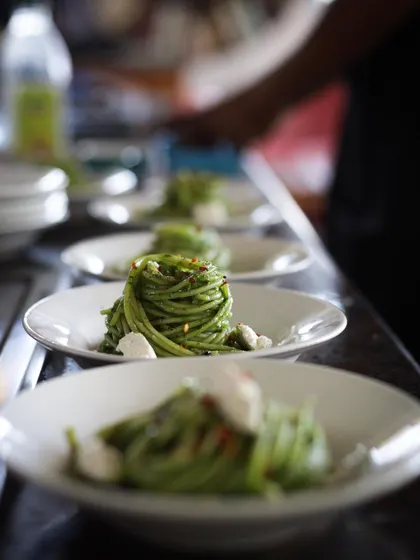 Plating a line of spinach pesto spaghetti. Consistency and attention to detail are drilled into our students for professional service.