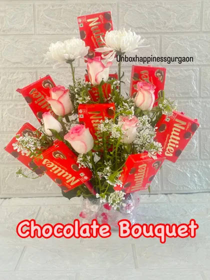Another view of the chocolate and flower bouquet, showcasing the fresh white chrysanthemums and pink roses.