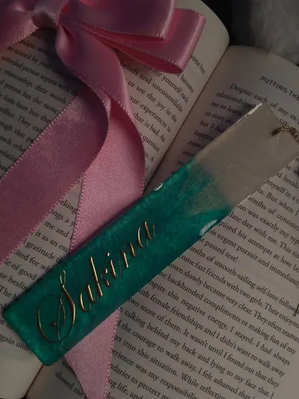 For the book lovers, I create personalized resin bookmarks. This one was made with the name 'Sakina' in a beautiful gold script, set in a teal and clear resin design with a matching tassel. It makes reading feel a little more special.