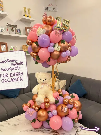 A custom-made teddy bear balloon bouquet for a 15th birthday. This tiered arrangement is full of playful details like butterflies and a mix of pink and chrome balloons.