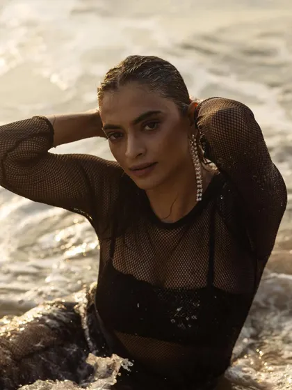 A close-up shot in the water, focusing on the wet-look hair and dramatic drop earrings that add a touch of glamour.