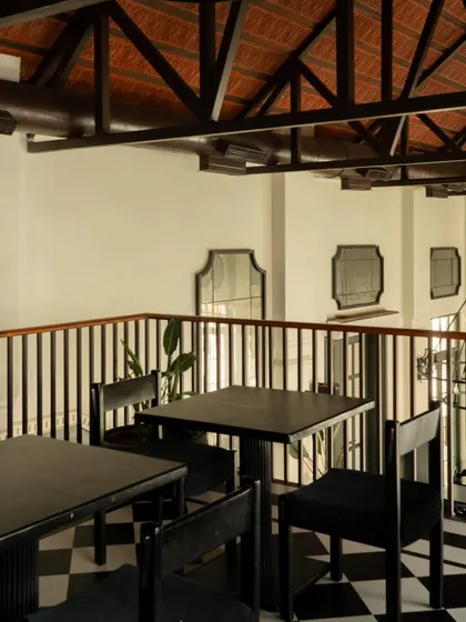 The mezzanine level at Elgin Cafe offers a more intimate dining perspective. The exposed roof trusses and simple, dark furniture continue the narrative of honest materiality and functional elegance.