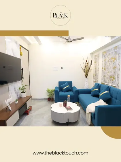 A bright and modern living room with a vibrant blue sofa set and a unique floral-shaped coffee table. The feature wall with textured wallpaper adds a touch of luxury, making the space feel both stylish and welcoming.