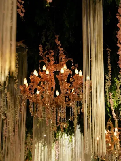 A close-up of a beautiful chandelier surrounded by hanging floral strings. This type of ceiling treatment can transform a venue, adding depth and romance to the atmosphere.