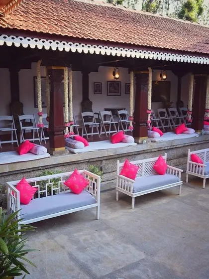 The seating arrangement for the Thottimane wedding. We combined modern benches with traditional floor seating, using vibrant pink cushions to add a pop of color against the venue's rustic architecture.