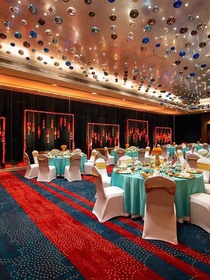 A vibrant 'Sajjangoth' dinner with a unique color palette. The turquoise linens, marigold centerpieces, and hanging glass bubbles created a festive and elegant setting for this traditional Marwari sit-down meal.