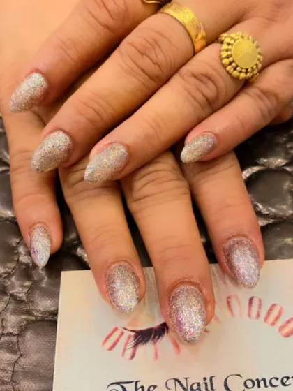A beautiful set of almond-shaped nails with a full coating of iridescent silver glitter. This design catches the light beautifully, showing hints of different colors.