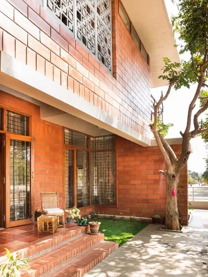 The small porch and garden at the Reshma Residence serve as a simple yet effective link to the outdoors. This space provides a pleasant seating area and a green buffer from the street, enhancing the home's connection to nature.