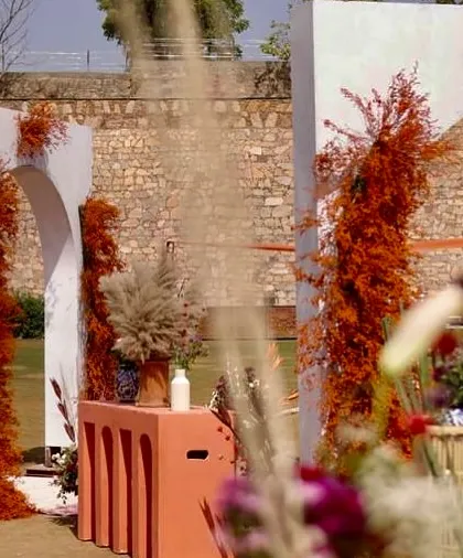 An artfully framed view of the Haldi setup, showcasing the layers of texture from the stone wall, modern arches, and rustic foliage.