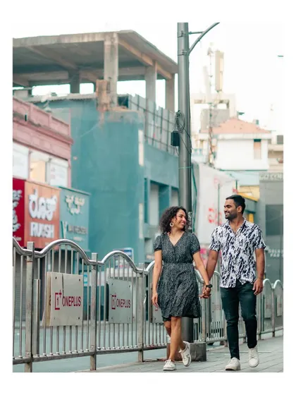 A candid shot of the couple walking hand-in-hand along a city railing.