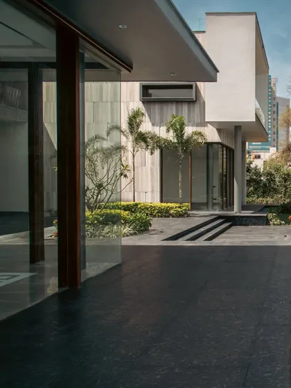 From this angle at Rosewood Farmhouse, the dark flooring of the veranda extends outwards, blurring the line between the entrance and the surrounding patio. This creates a continuous ground plane that connects different zones of the landscape.