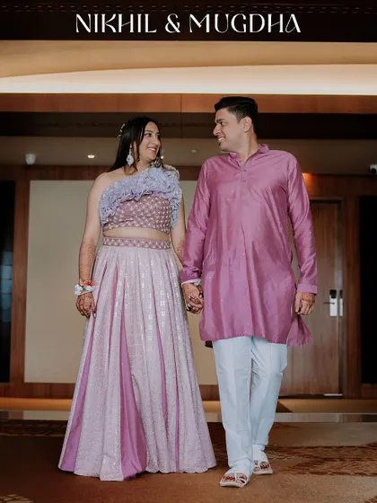 A full-length shot of the couple in their coordinated outfits for a pre-wedding event like the Haldi or Mehendi.