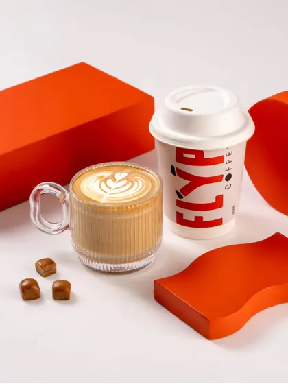 A shot showcasing Flyp Coffee's offerings in both a glass mug and a takeaway cup, highlighting options for dine-in or to-go.