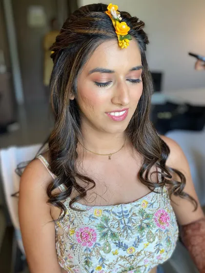 Soft and pretty makeup for a Haldi look, with a touch of yellow floral accessory in her hair.