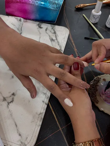 A close-up of a student practicing detailed nail art with a fine brush. Precision and patience are two of the most important skills we teach.