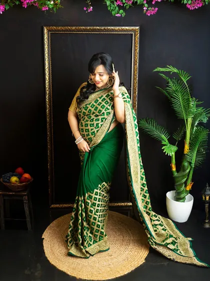 A full-length portrait in a traditional green saree. The setup includes natural elements like a potted plant to complement the color scheme.