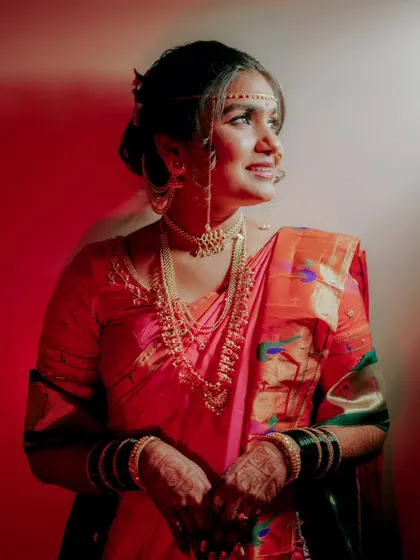 An artistic portrait of the bride, with dramatic red lighting highlighting her traditional jewelry and attire.